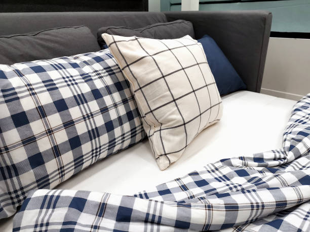 istock Blue and white plaid pillows and blankets lying on the white mattress. 1565068027