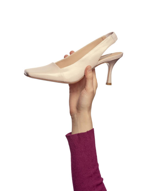 istock A woman's hand holding a glossy patent-leather open-back shoe isolated on a white background. Fashionable footwear in hand 1565080986