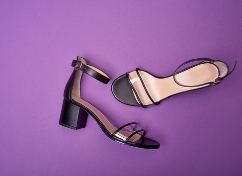 Stylish open-toe women's shoes with block heels, clear vamps, ankle straps and beige insoles, isolated on a purple background. Fashion photography