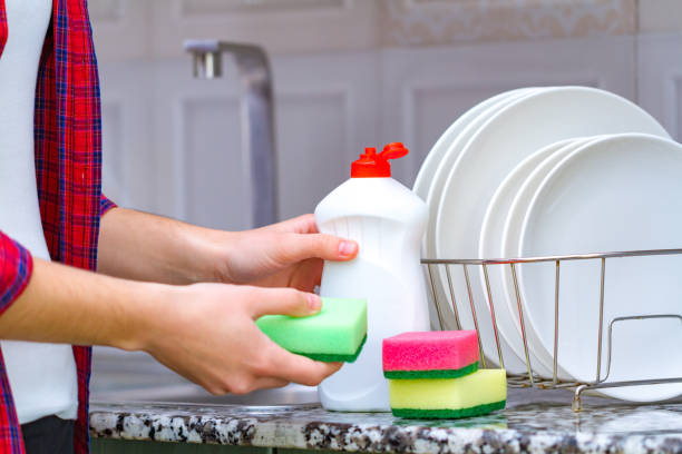 istock Different clean plates in dish drying rack, dish sponges and dishwashing detergent on the table on kitchen counter 1565085166