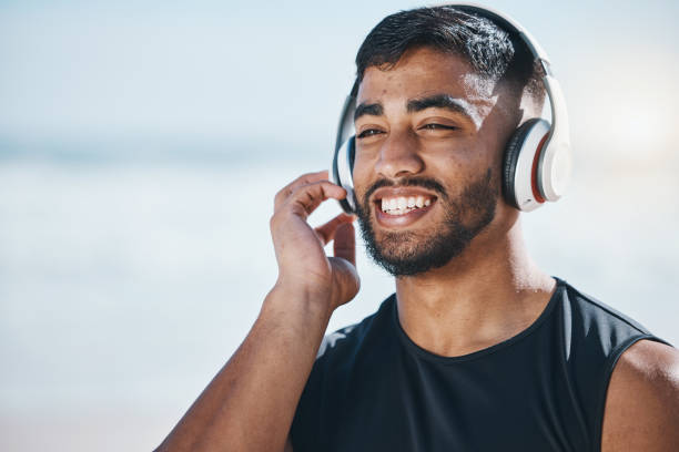 szczęśliwy, plażowy i człowiek z muzyką do fitnessu, motywacją do biegania i pomysłami w naturze. uśmiech, dobre samopoczucie i sportowiec słuchający lub transmitujący podcast podczas treningu lub ćwiczenia wzroku nad morzem - peace on earth audio zdjęcia i obrazy z banku zdjęć