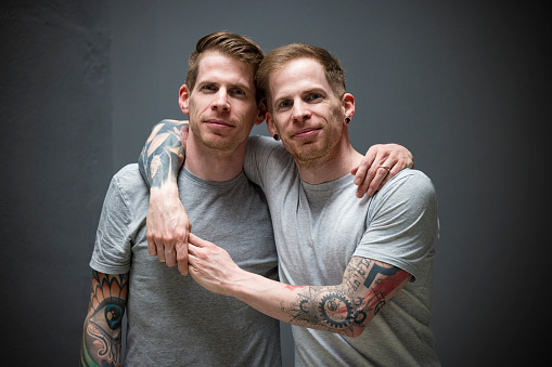 tattooed twin brothers hugging.
