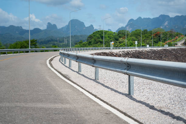 Asphalt road with safety barrier fence of the overpass way above the dam, with scenic beautiful view of mountain as bakground. Transportation and travel scene photo, selective focus.
