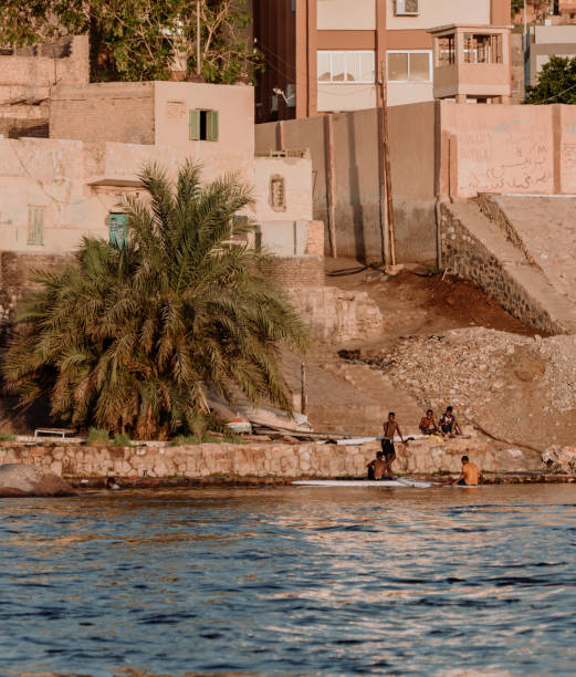 View across large wide river Nile in Egypt through rural countryside landscape with beautiful dramatic orange sunset and clouds in sky