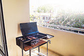 Barbecue with a portbale grill in the balcony of apartment. Traditional roast beef of Argentina. Asado. Copy space.