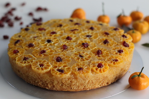 Orange upside down cake. Home baked Orange upside down cake with baby orange or clementine slices on the top along with dried cranberries for decoration. Shot on white background