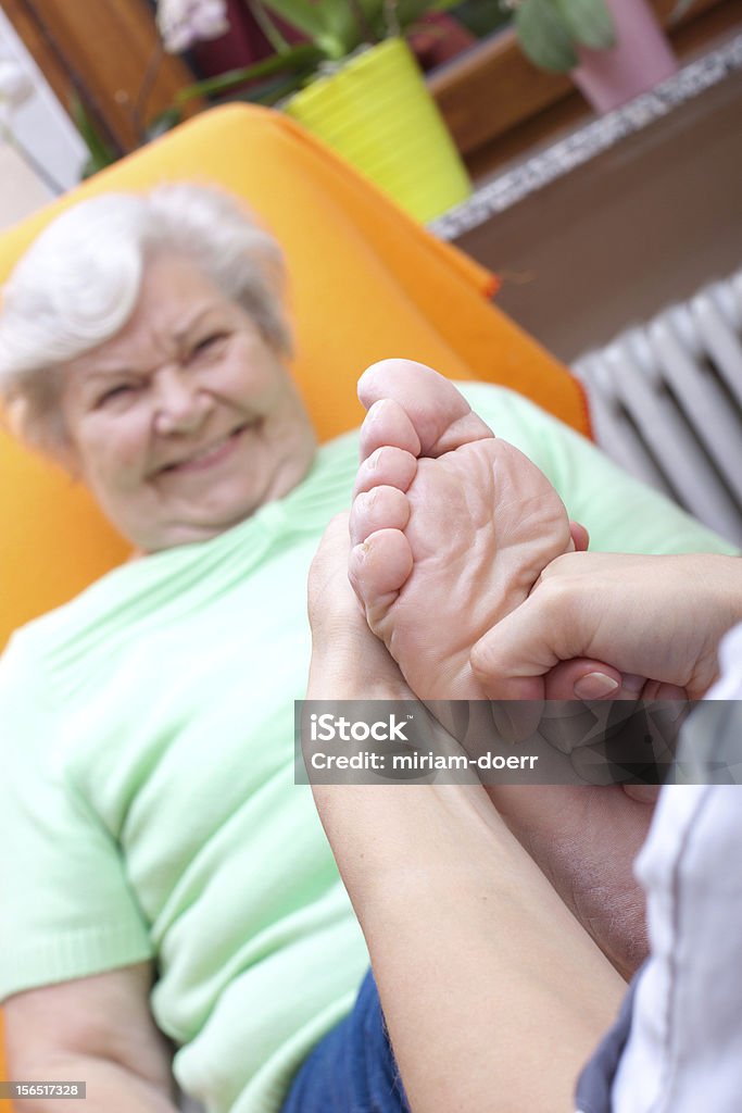 Infermiera Massaggiare un piede di un paziente - Foto stock royalty-free di 70-79 anni