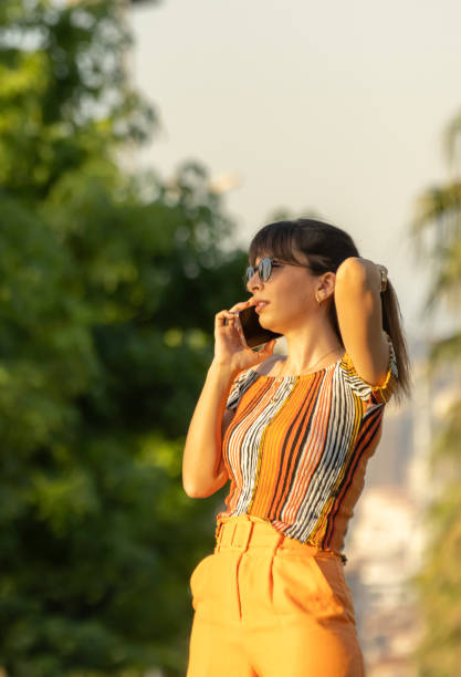 istock Young woman is talking on mobile phone at sunset. 1565177738