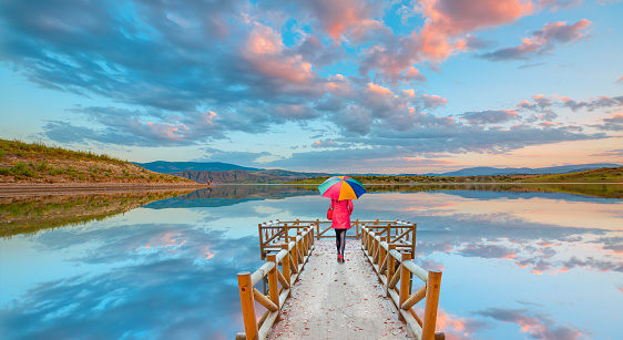 Beautiful woman holding multicolored umbrella walking on the piere