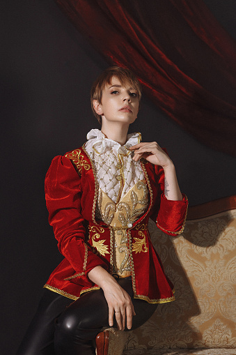 A woman in a red vintage jacket embroidered with gold patterns. Vintage portrait of a young lady in a red ballet costume in the Baroque style.