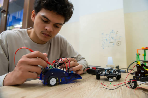 istock Teenage students build learning with robotic vehicles at desks in STEM engineering science education classes. 1565204547