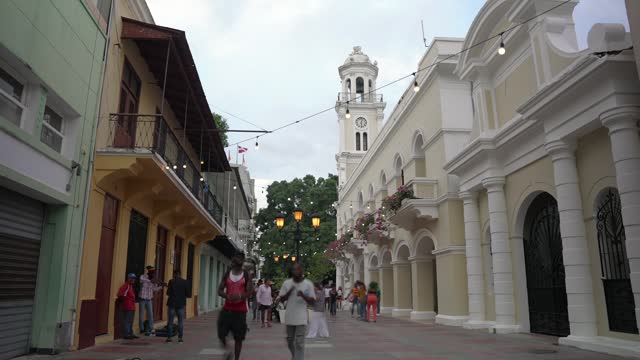 Dominican Republic, Santo Domingo - July 17, 2023: Timelapse of people walk by Calle El Conde in Colonial City at sunset. Palacio Consistorial view. Top things to do for tourists in the capital.