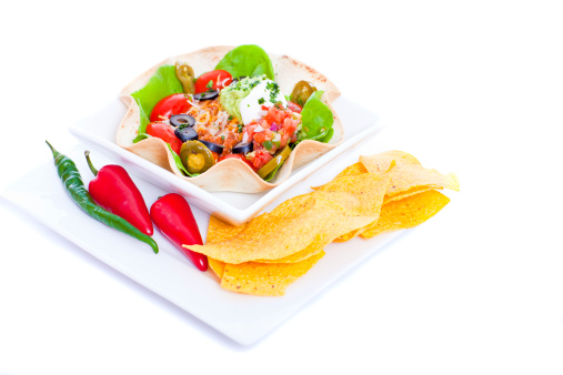 Taco salad in a baked tortilla on white background
