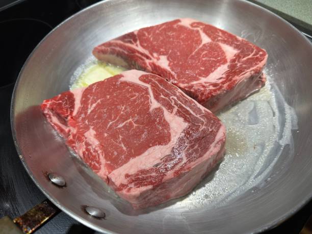 istock Raw ribeye steaks in a frying pan 1565240984
