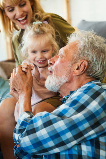 Happy grandfather and cute little toddler granddaughter, adorable child eating together ice cream. Family tasting sweet icecream, baby girl feeding senior man