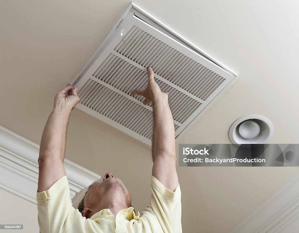 Senior homme climatisation filtre d'ouverture dans le plafond - Photo de Purificateur d'air libre de droits