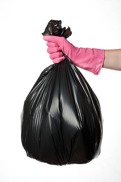 A pink gloved hand holding a rubbish bag stock photo