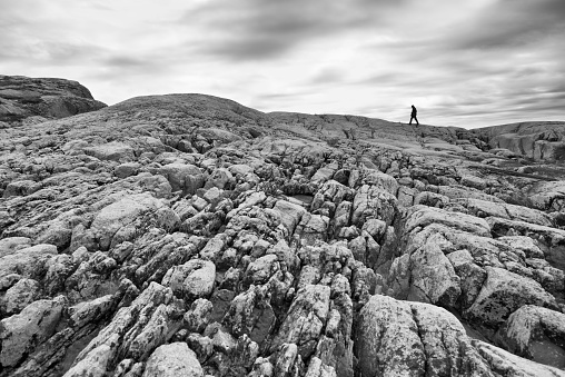 Silhouette of lonely young man that going up on the rock. Norwegian fjords. Black&White.