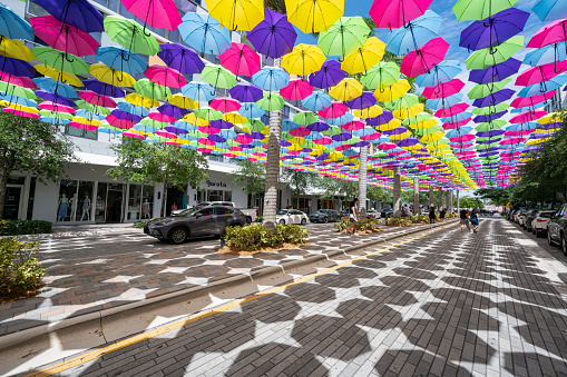 Miami, Florida - April 9, 2023 - Visitors enjoy canopy of colorful umbrellas suspended over Doral CityPlace boulevard on sunny Sunday morning.
