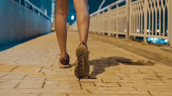 Closeup of happy young sporty Asian women wear sports outfits running enjoy cardio through the city streets over bridge at night. Running club and exercise outdoor concept.