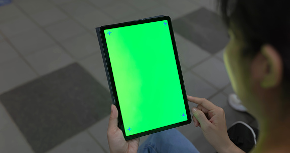 close up rear view asian woman is using green screen digital tablet while waiting car at subway station platform