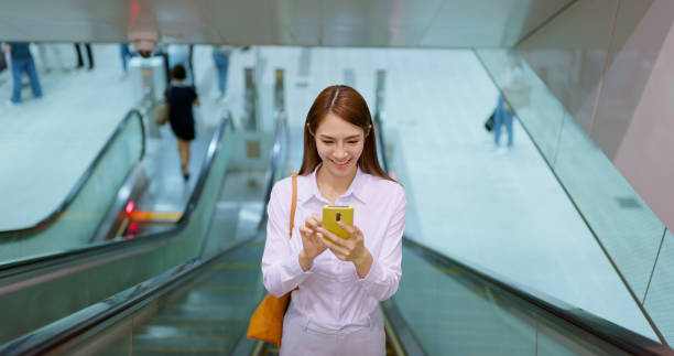 istock woman use phone on escalator 1565434551