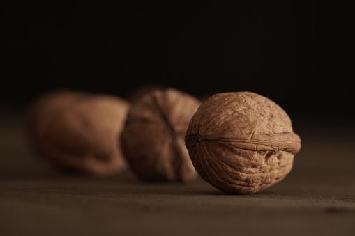 Close-up of walnut kernels and shelled nuts on a wooden table on a dark background.Healthy food, quick snack