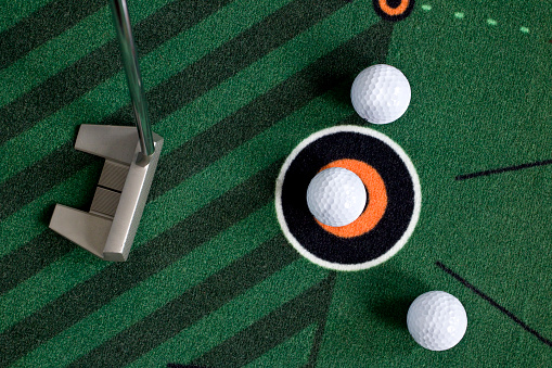 Indoor putting with golf balls on practice mat