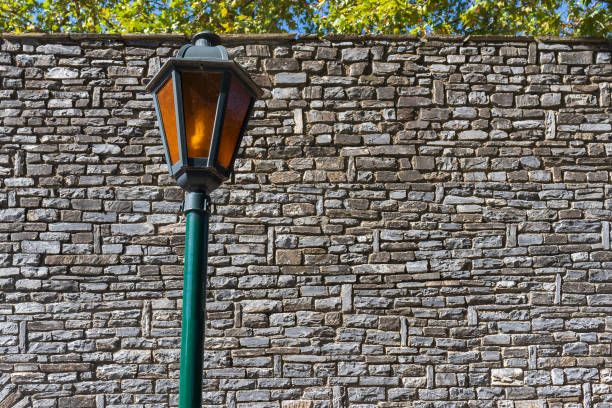 Street light in front of old gray stone brick wall