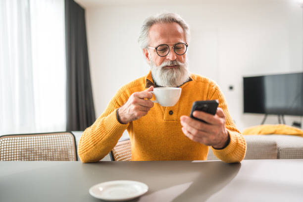 istock Caucasian Businessman Drinking Coffee And Using Smartphone At Home 1565503128