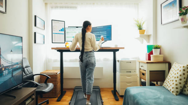 istock Woman working at standing desk is using credit card while walking at treadmill 1565503154