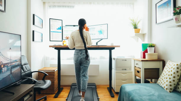 Woman at home office is walking on under desk treadmill