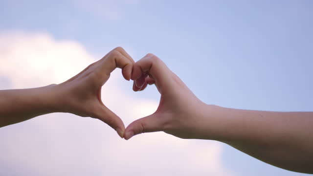 Couple forming a heartshape using their hands.