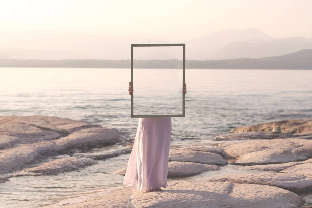 istock woman holding a frame that surreally reflects the landscape , abstract concept 1565534517