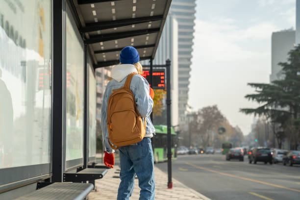 istock Millennial gut tourist with backpack waiting at bus stop 1565566021