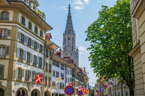 Cathedral tower bell and flags among the street in the historic street in the old town of Bern, Switzerland