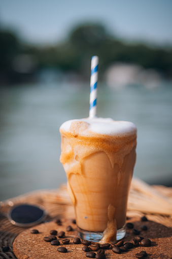 Ice latte coffee on a wooden table with a blurred beach background.