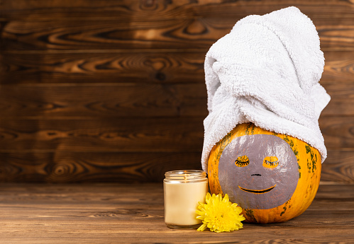Pumpkins with face mask and towel on white background, burning candle, cosmetics with copy space