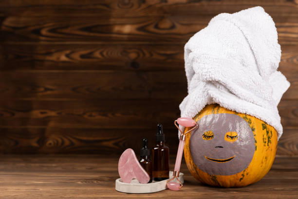 istock Pumpkins with face mask and towel on white background, burning candle, cosmetics with copy space 1565678954