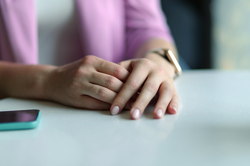 Female hands lie on a white table next to a smartphone, on one hand is a smart watch, digital intoxication, gadget addiction.