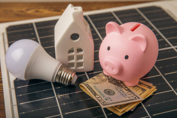 istock Flat lay composition with solar panel, led lamp and piggy bank on background. The concept of saving money and clean energy. The concept of ecology and sustainable development. 1565680557