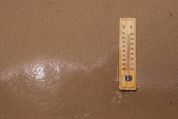 istock Thermometer on sand showing high temperature. Hot weather and climate concept 1565682183