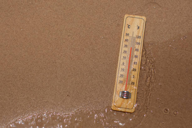 istock Thermometer on sand showing high temperature. Hot weather and climate concept 1565682201