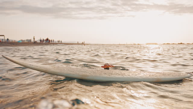 Young Female Surfer Submerging Her Head Into The Sea While Holding Her Surfboard
