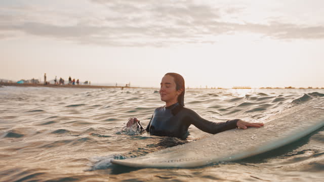 Young Female Surfer Gets Her Head Out Of The Water While Holding Her Surfboard
