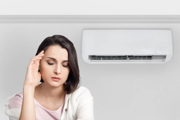 istock Woman holding her head while experiencing a cold and feeling unwell due to the air conditioner 1565705570