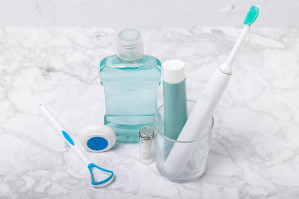 Electronic ultrasonic toothbrush, mouthwash, floss, tongue cleaner and toothpaste on blue textured background. Items for dental care and caries prevention in the bathroom. Dentistry concept. Copy spac cepillo de dientes ultrasónico electrónico, enjuague bucal, hilo dental, limpiador de lengua y pasta de dientes sobre fondo de textura azul. artículos para el cuidado dental y la prevención de caries en el baño. concepto de odontología. espacio de co