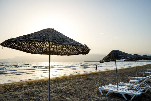istock People walks on beach at sunset, sunbed, beach parasol 1565715345
