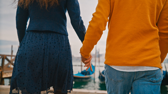 Heterosexual couple holding hands in front of sea during vacation