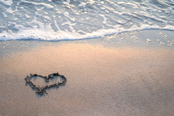 istock Heart drawn on the beach near foamy sea waves, empty space, copy space 1565719893